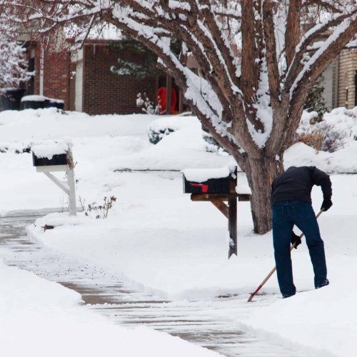 A man shoceling his sidewalk.