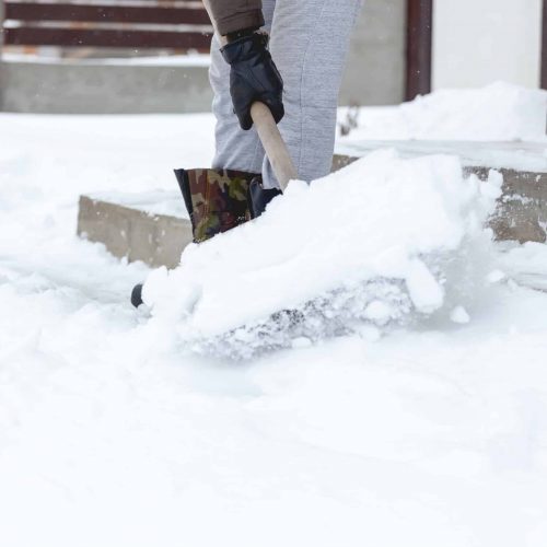 A Man shoveling snow from the steps of his house